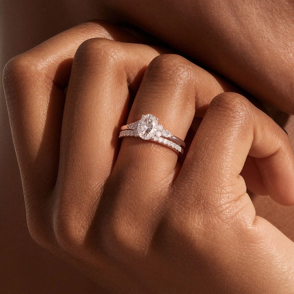 A Woman Wears a Oval Cut Moissanite Bridal Ring Set with Classic Straight Band