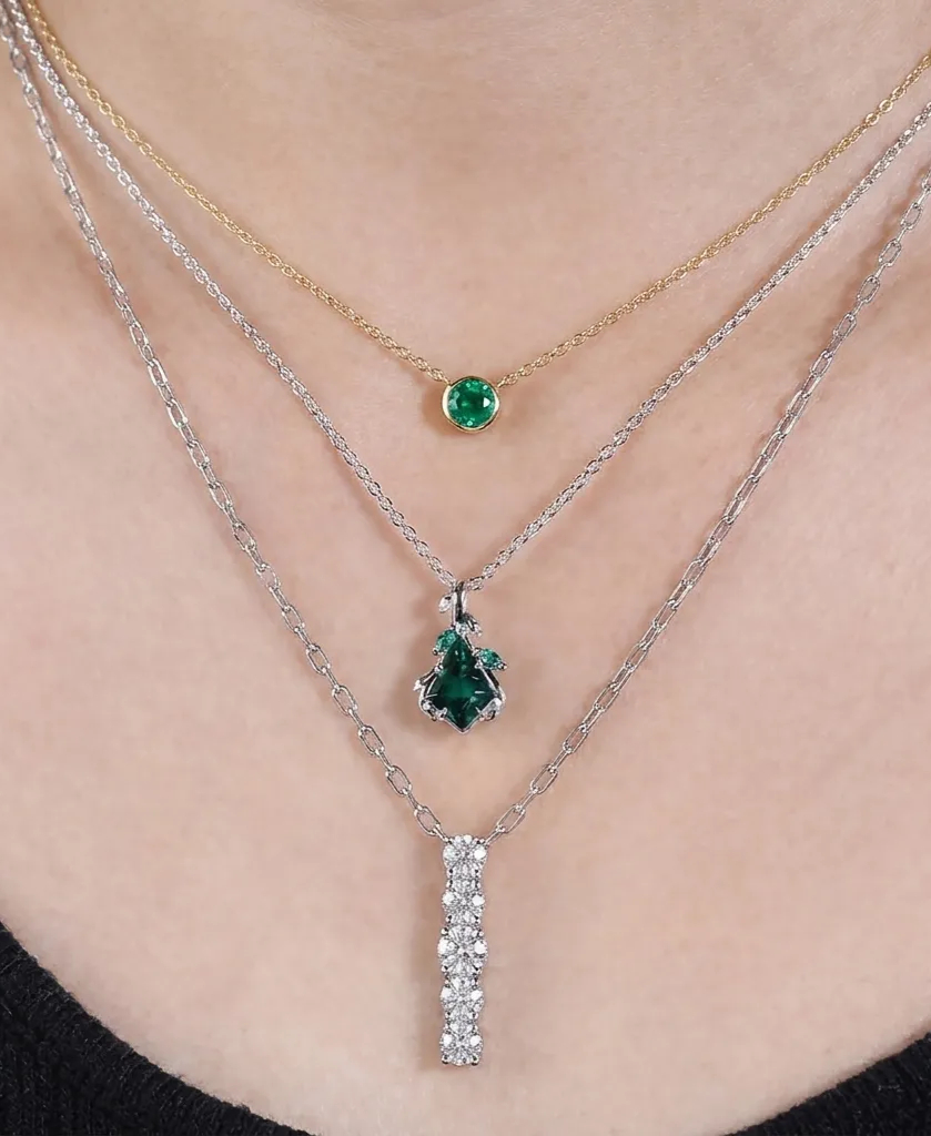 Professional necklace layering guide MollyJewelryUS all-sterling silver geometric stack featuring a round emerald, a triangle emerald cluster, and a vertical diamond bar pendant